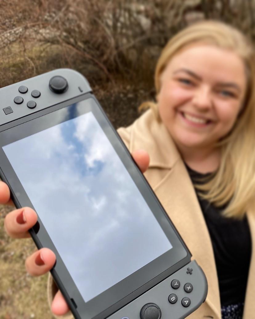 Bilde av kvinne som holder opp en Nintendo Switch. Foto. 